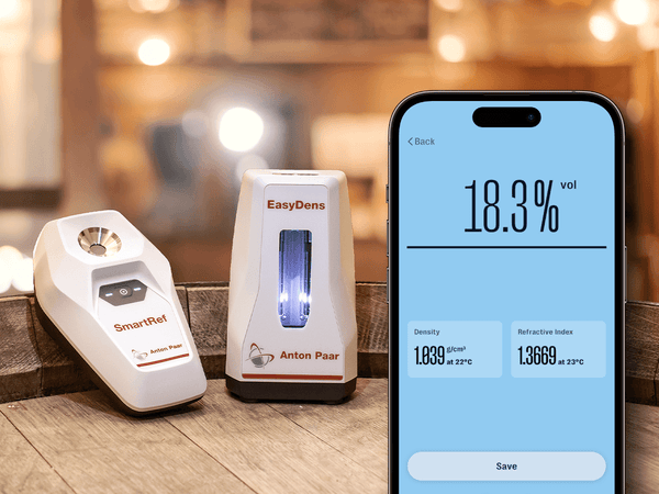 Smartphone screen showing alcohol volume measurement beside EasyDens by Anton Paar Digital Density Meter and SmartRef Digital Refractometer, tools for precise spirit analysis.