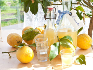 Homemade Limoncello bottles with lemons around and  small drinking glasses