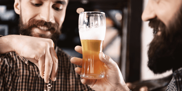 Two men engaging in beer tasting, evaluating the quality of a craft beer pour, perfect for utilizing the EasyDens by Anton Paar Digital Density Meter for Beer to ensure optimal brewing results.